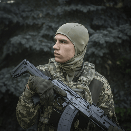 Soldat iført M-Tac Sweater-Ninja-Balaclava Premium i skovklædning, holder våben, optimal til fugthåndtering og komfort.