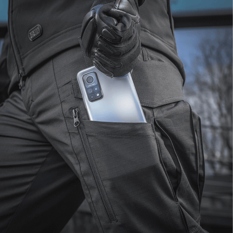 M-tac Taktiske Bukser Conquistador Gen. I Flex med fleksibelt Rip-stop materiale til udendørsaktiviteter, der viser en lomme med telefon.