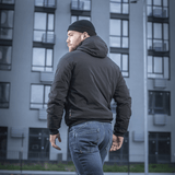 Mand iført M-Tac Rubicon Jakke Gen. II – Slidstærk og varm bomberjakke, står udendørs foran moderne bygning.