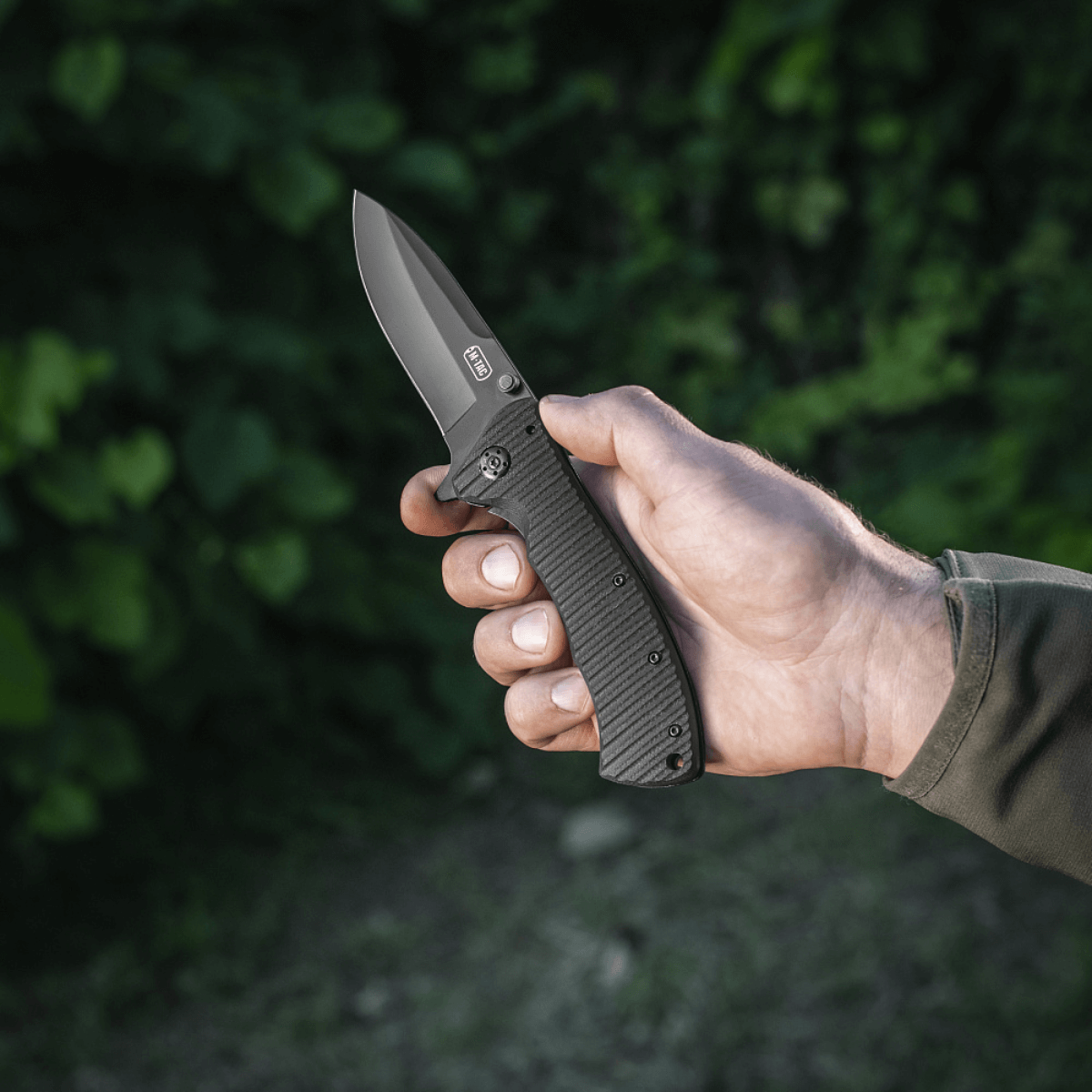 M-Tac Outdoor & Militær foldekniv - Type 7 med krom rustfrit stål klinge holdt i hånden, fremstillet til taktiske formål.