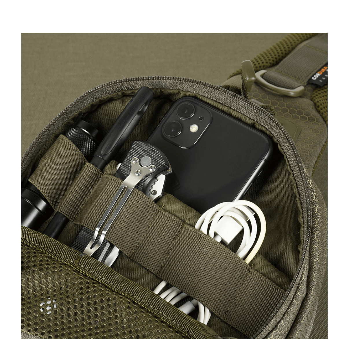 Detaljeret indblik i M-Tac Buckler Taske Elite Hex med lommer fyldt med værktøjer og elektronik, afslører funktionaliteten af det smarte design.